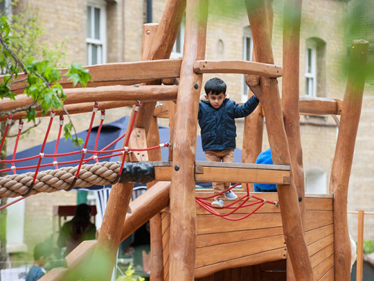 Boy on rope net on timber climbing unit