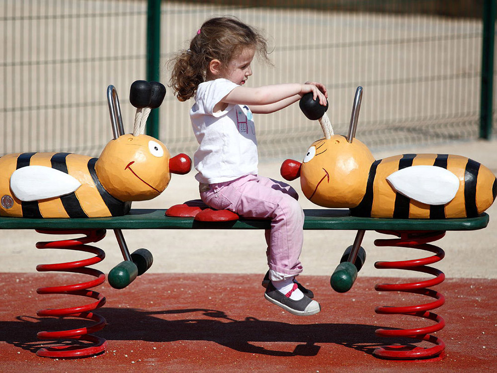Girl playing on bee seesaw springer
