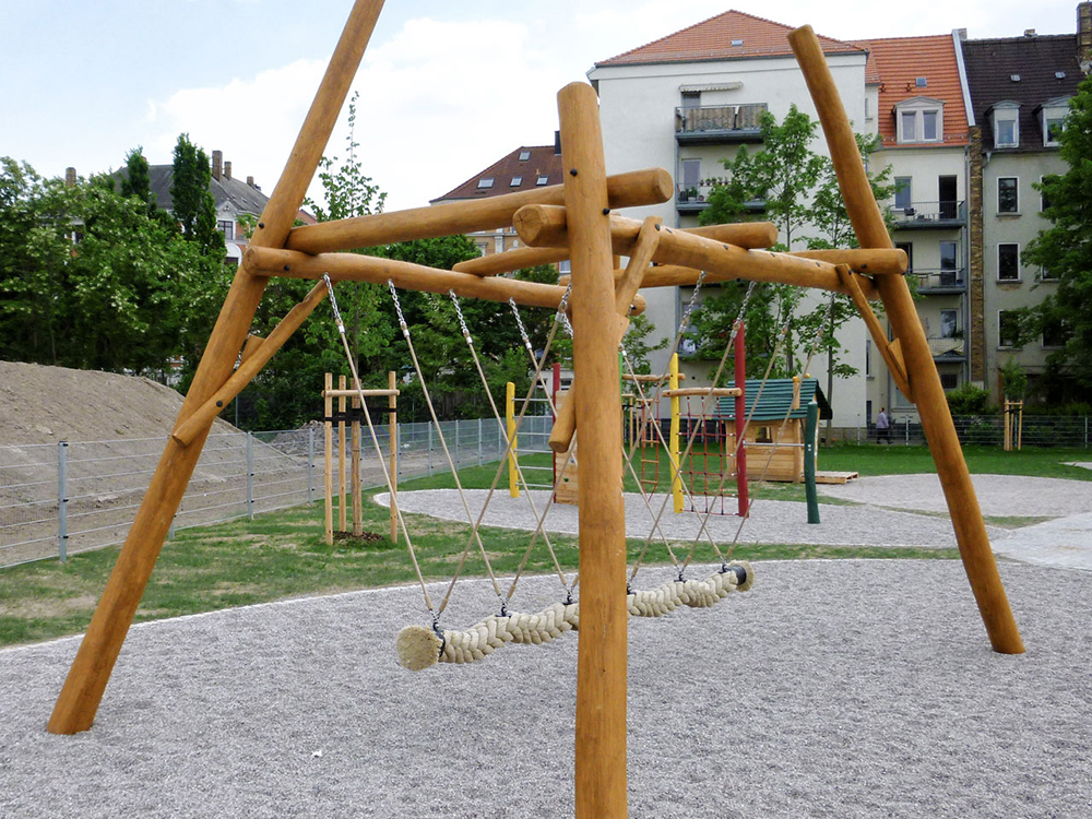 Timber framed rope swing with toddler play area in background